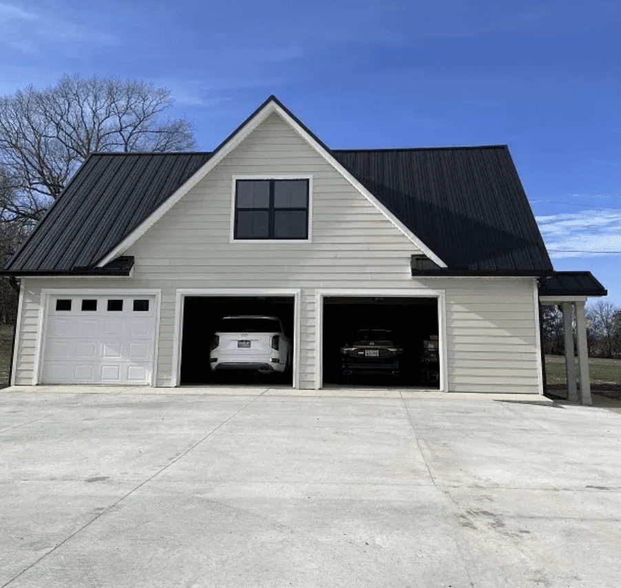 Three-bay custom garage with dark metal roof and upper-level window