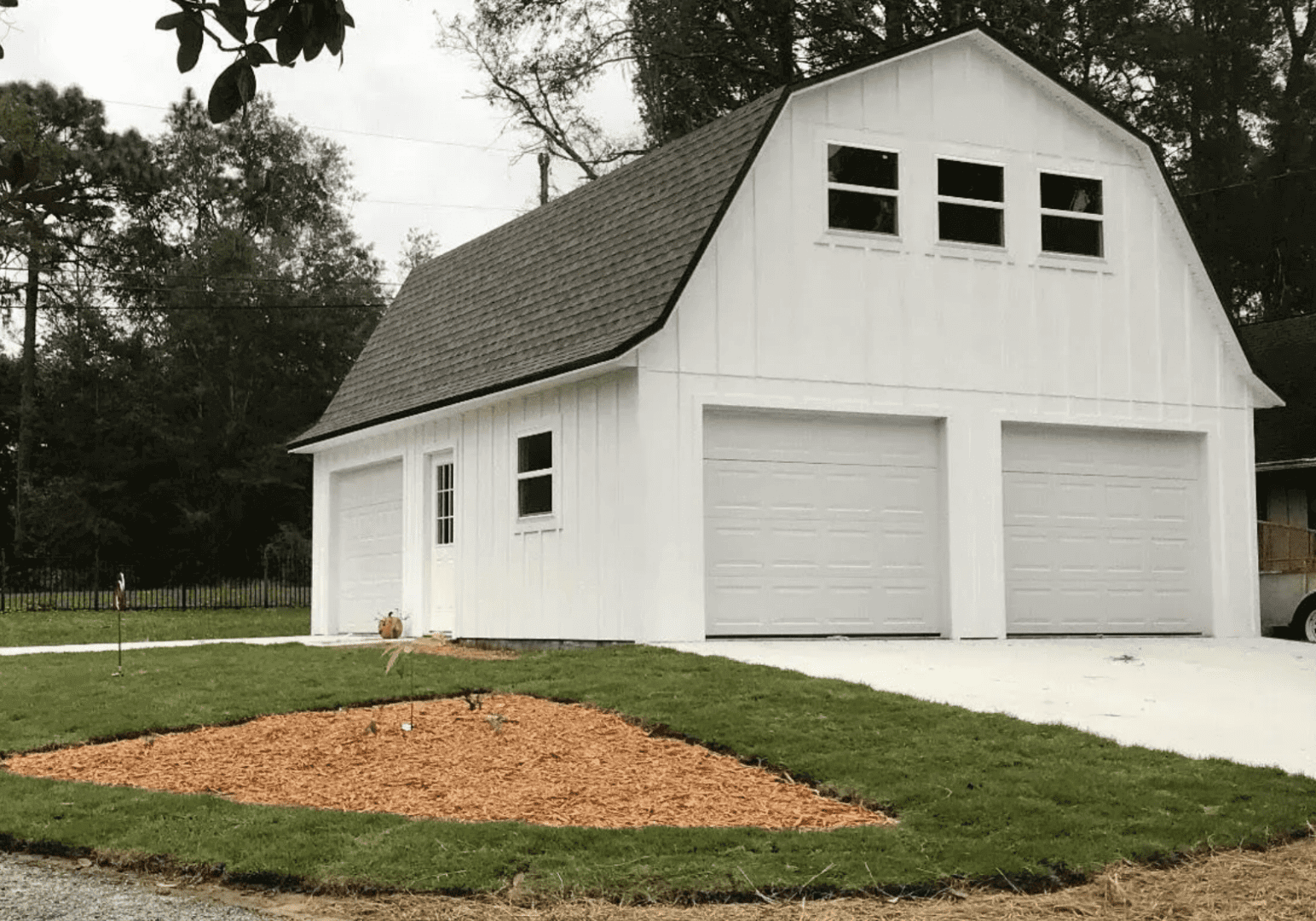 Large white detached multi-bay garage with tall roofline and multiple overhead doors