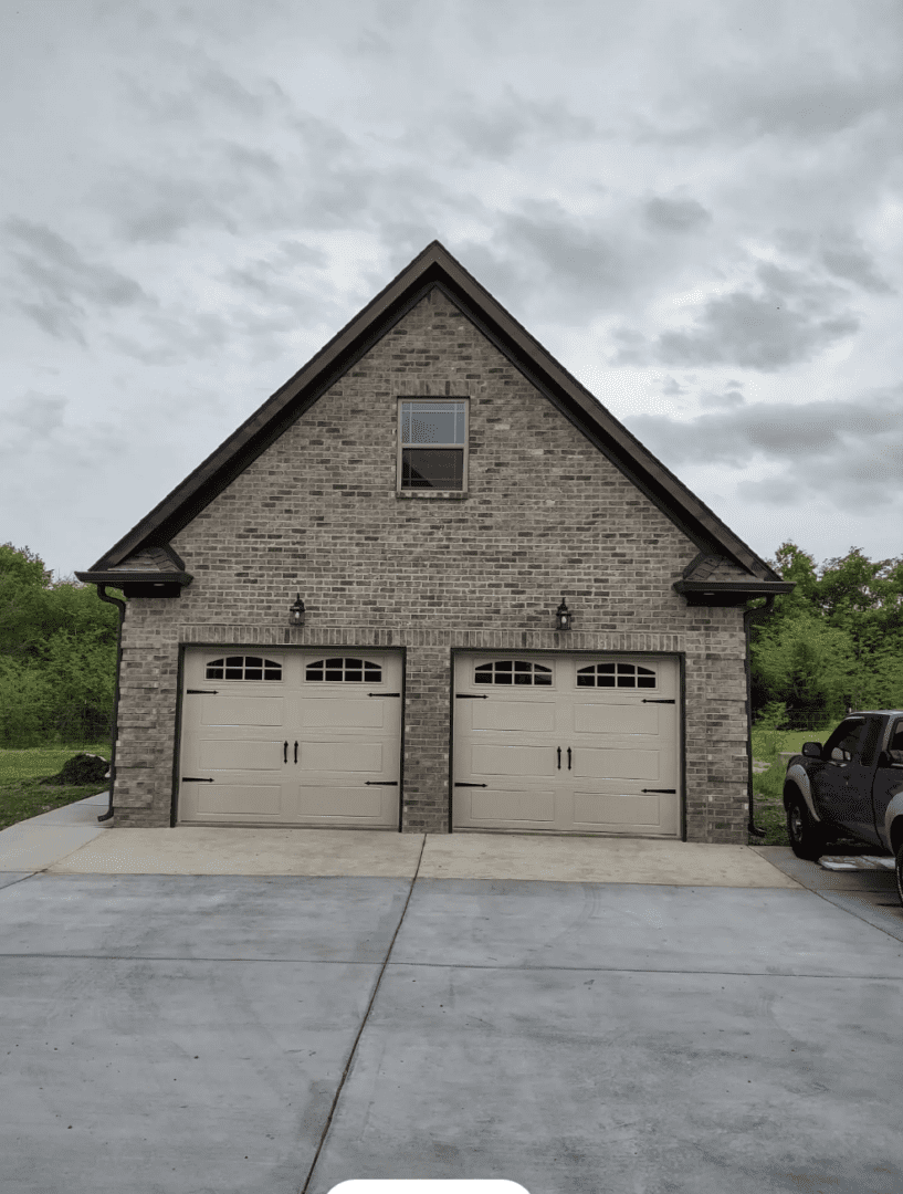 Brick front detached garage with two overhead doors and upper window