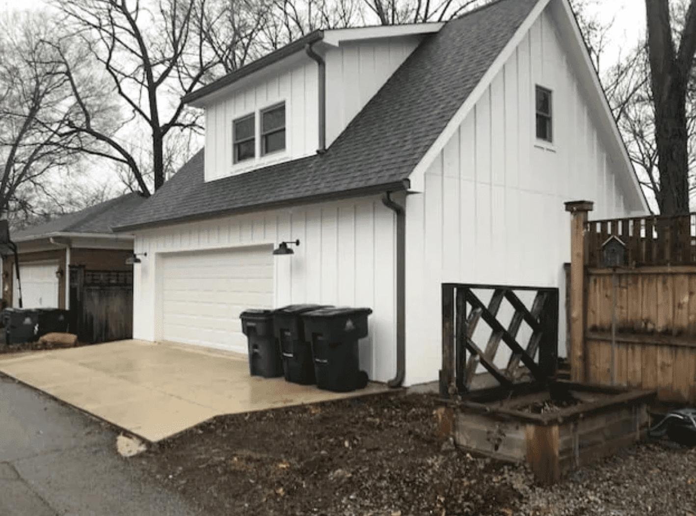 White board and batten garage with upper loft dormer and wide garage door