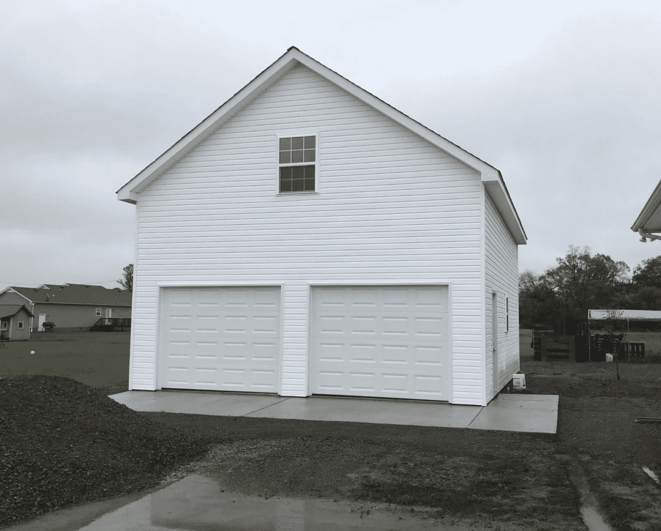 Tall detached garage with two garage doors and upper gable window